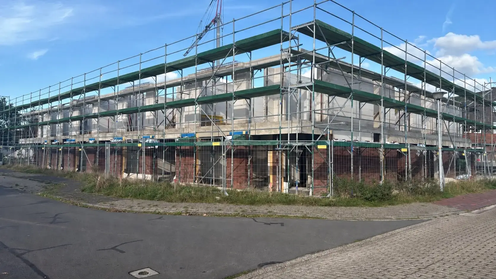 Großer Neubau mit mehrlagigem Fassadengerüst, von der Straßenecke gesehen